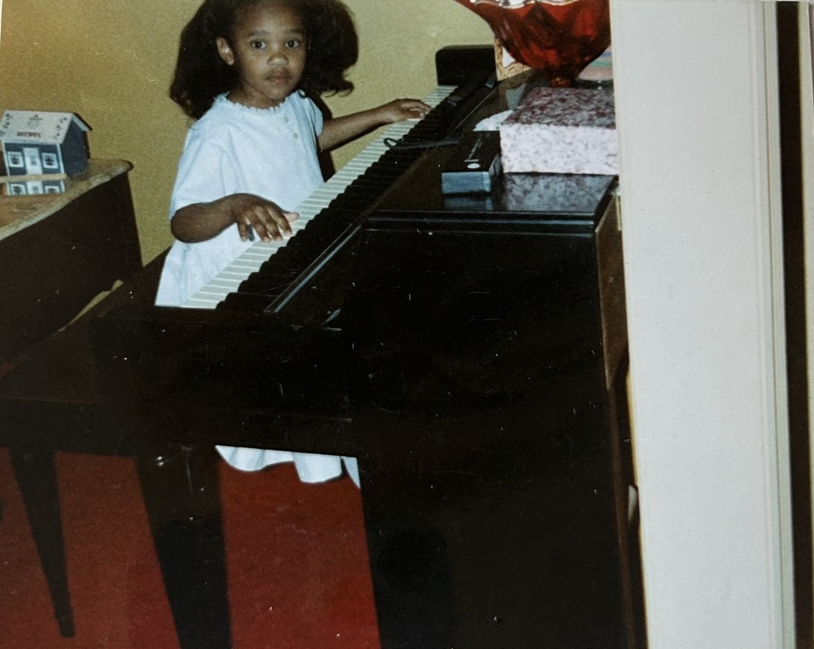 Destanee as a child sitting at a piano